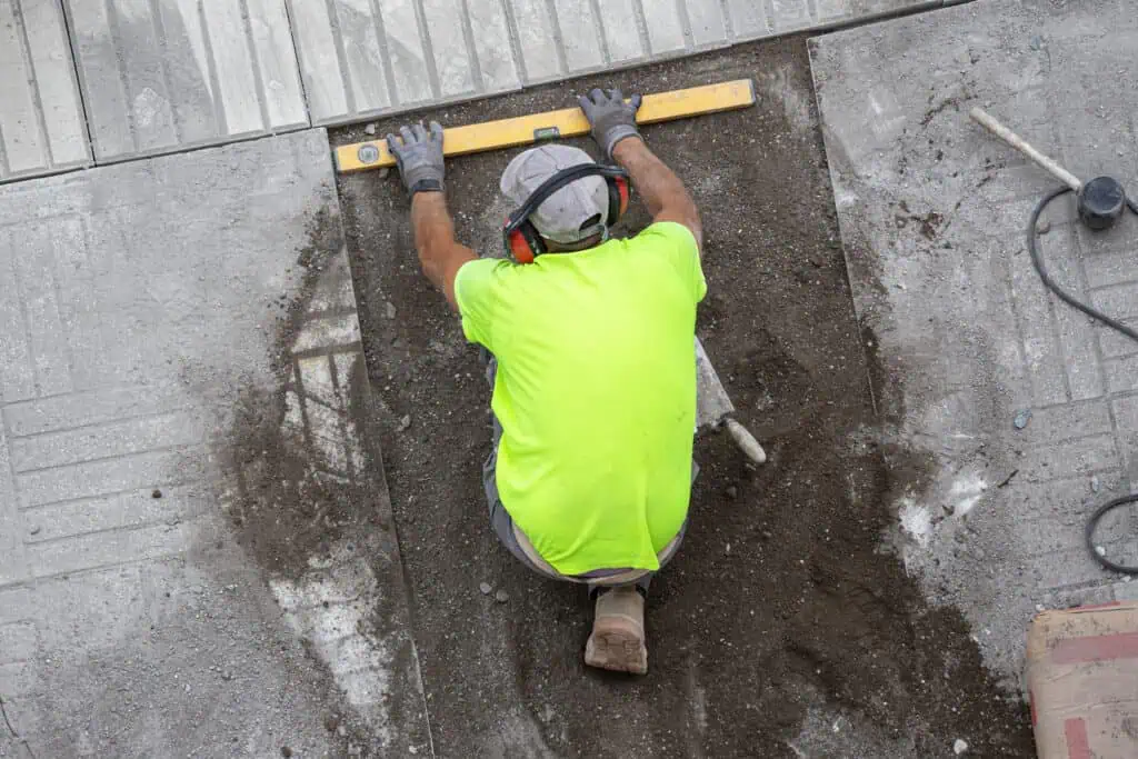 Worker leveling concrete surface with a spirit level at a construction site.